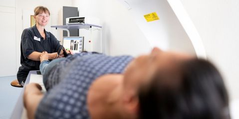 Pflegekraft bereitet Patientin zur Knochendichtemessung vor