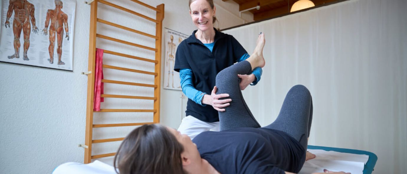 Therapeutin mobilisiert in der Physio das Bein der Patientin