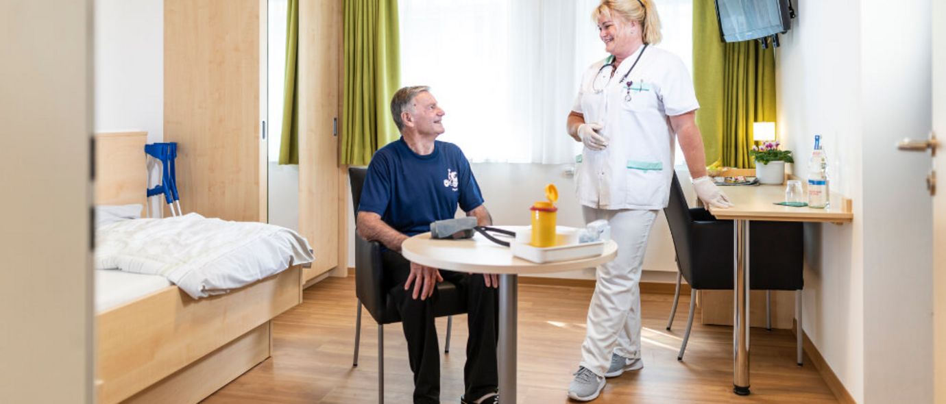 Pflegekraft spricht mit Patient in seinem Zimmer