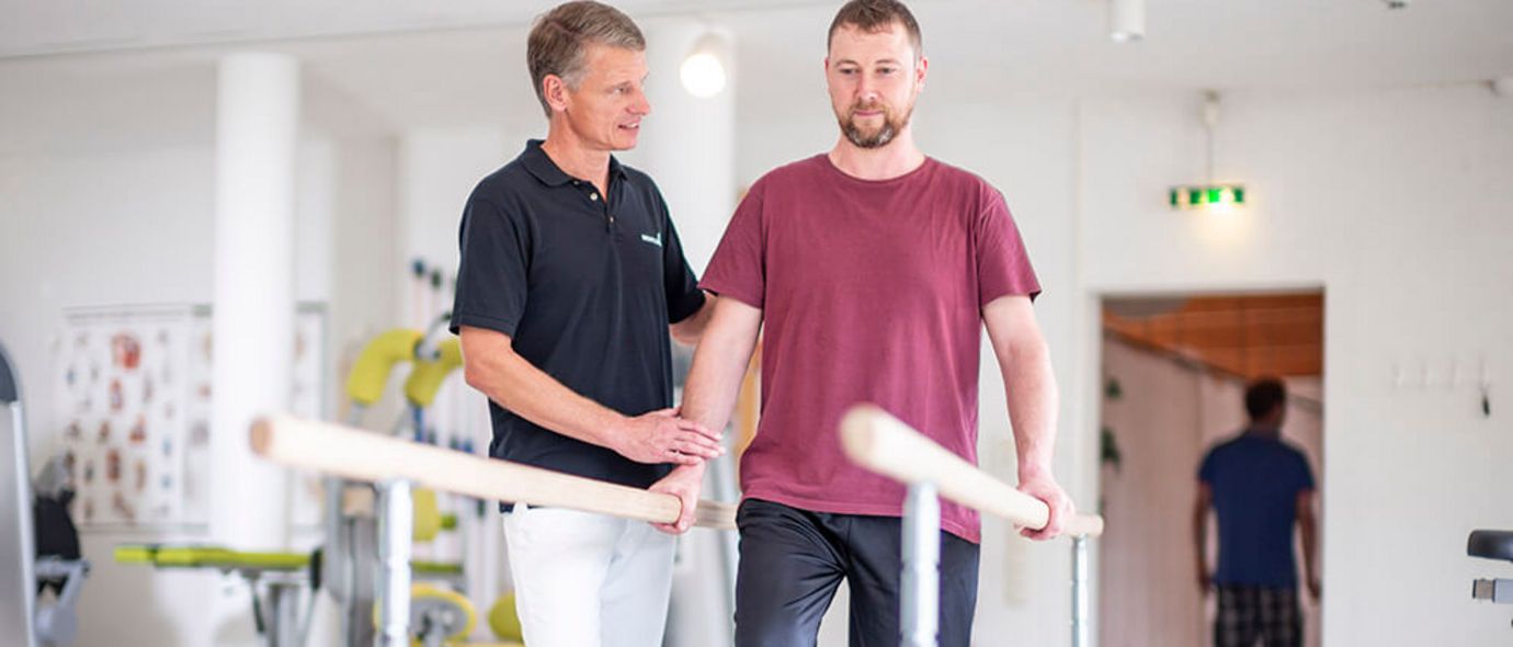 Therapeut unterstützt Patienten beim Gangtraining