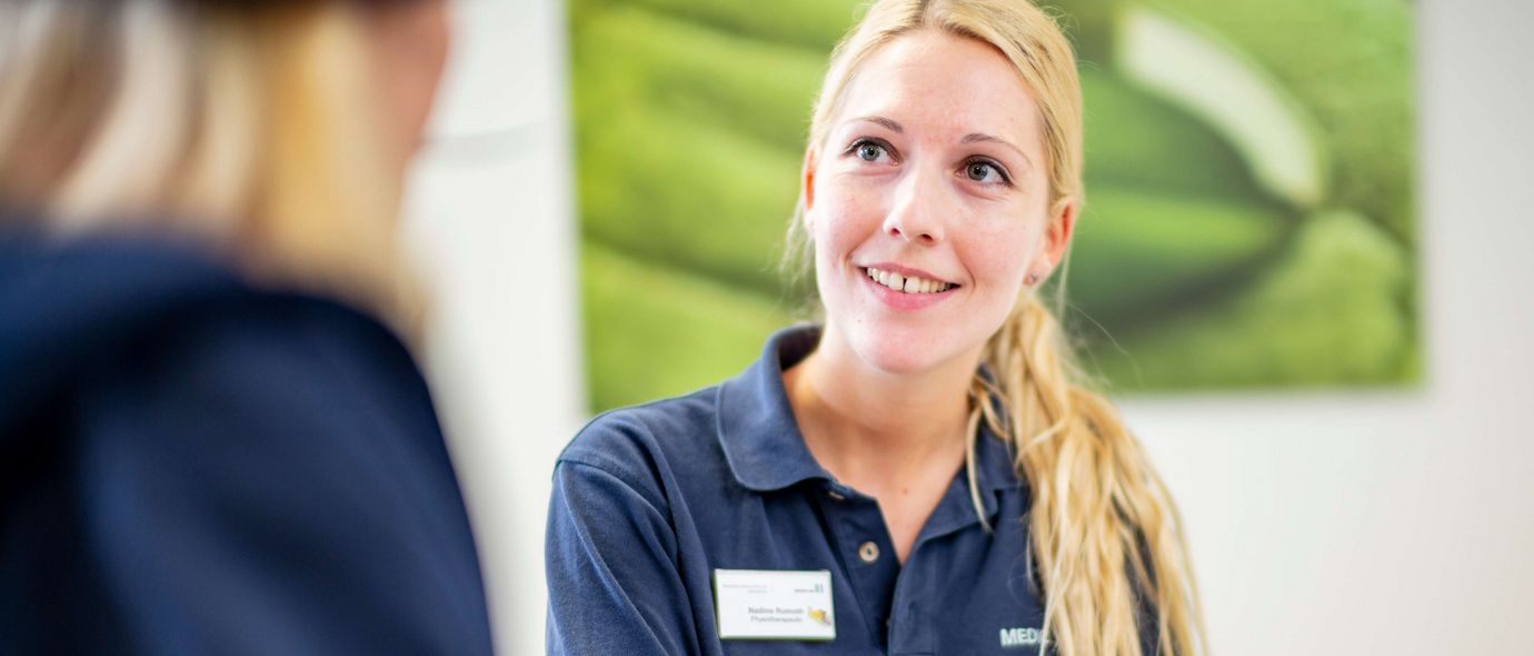 Eine Mitarbeiterin hilft einer Patientin beim Ausfüllen von Formularen