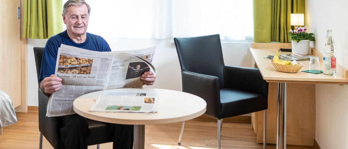 Patient liest Zeitung in seinem Zimmer