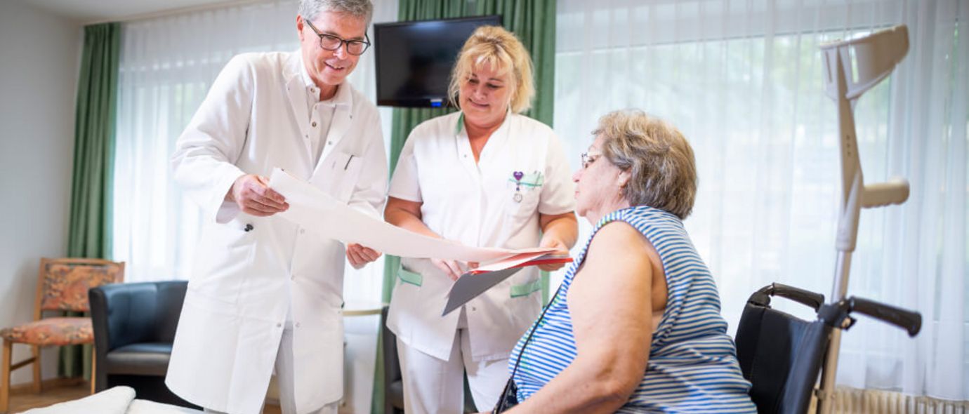 Patientin spricht mit Arzt und Pflegekraft während der Visite