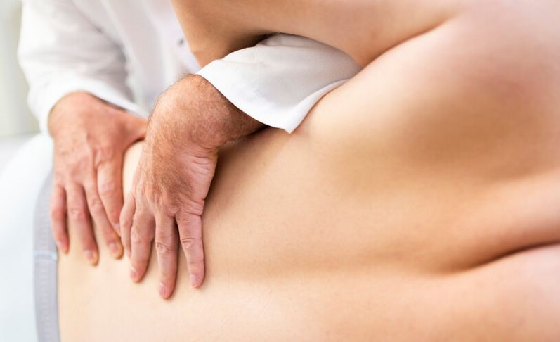Arzt prüft Rücken eines Patienten