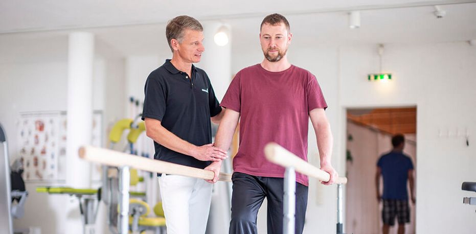 Therapeut unterstützt Patienten beim Gangtraining