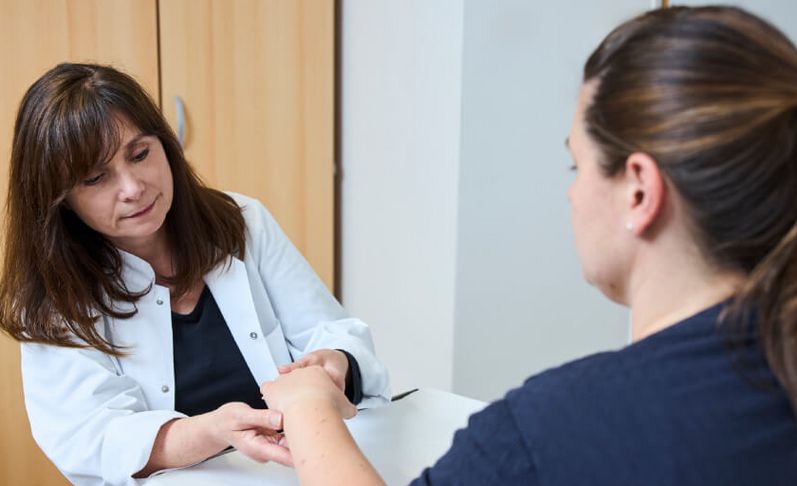 Ärztin untersucht die Hand einer Patientin