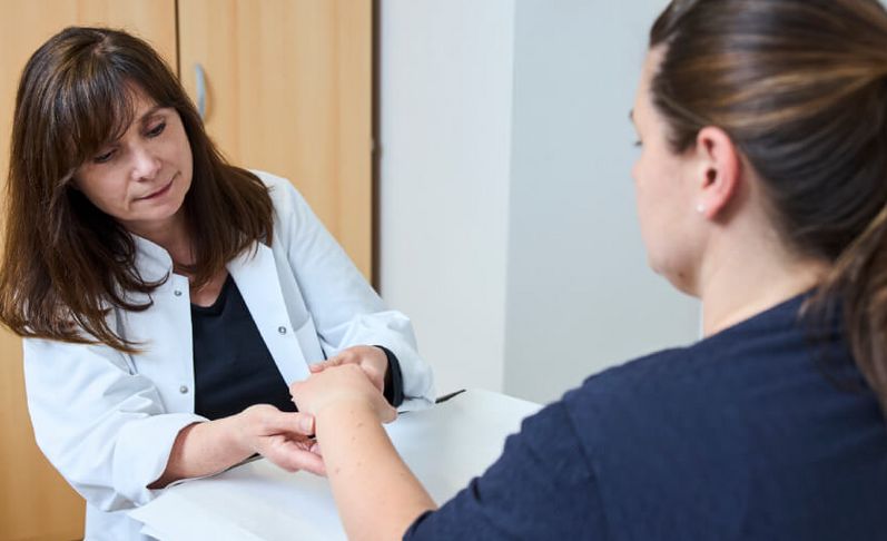 Ärztin untersucht die Hand einer Patientin