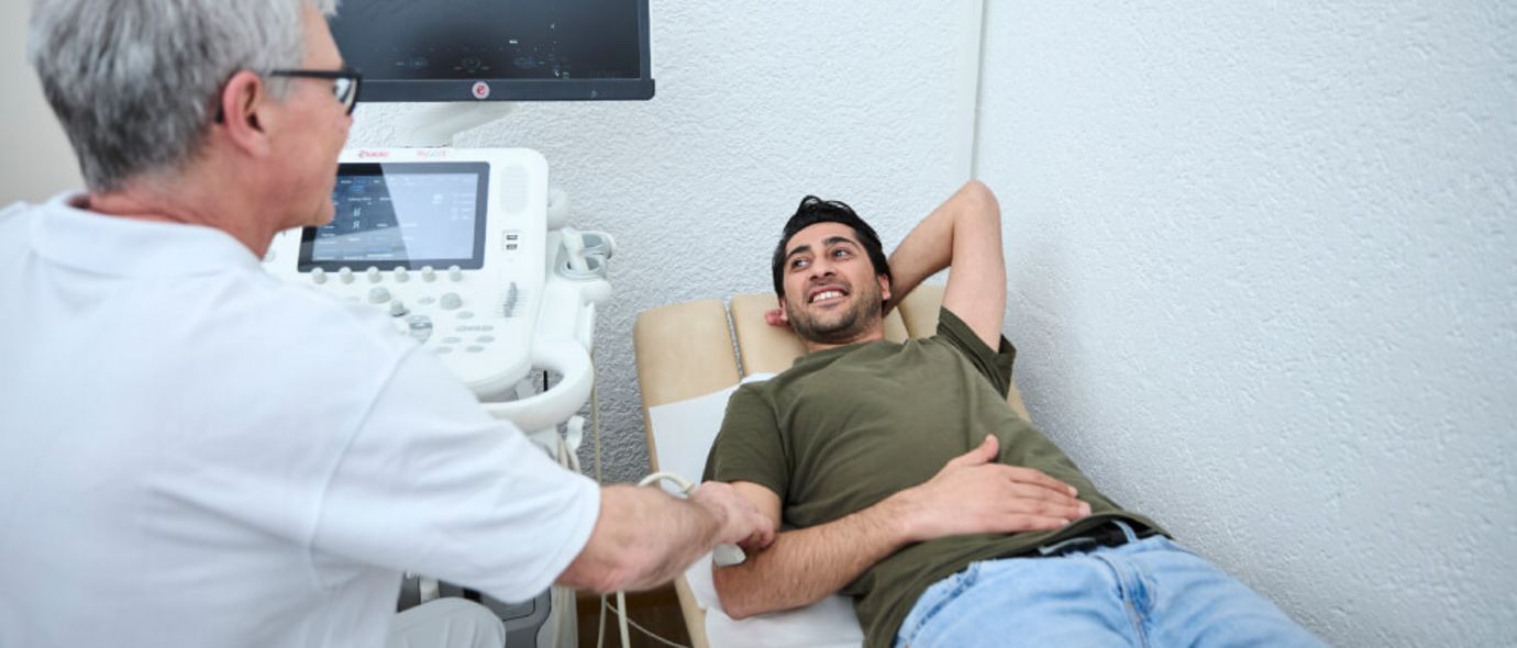 Ein Arzt untersucht per Ultraschall den Ellenbogen eines Patienten