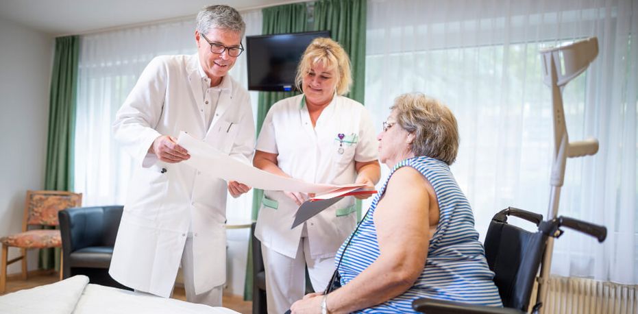 Patientin spricht mit Arzt und Pflegekraft während der Visite