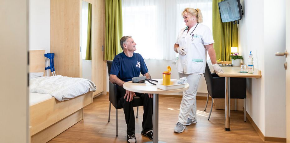 Pflegekraft spricht mit Patient in seinem Zimmer