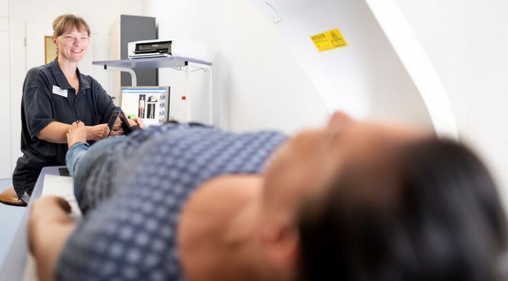 Pflegekraft bereitet Patientin zur Knochendichtemessung vor