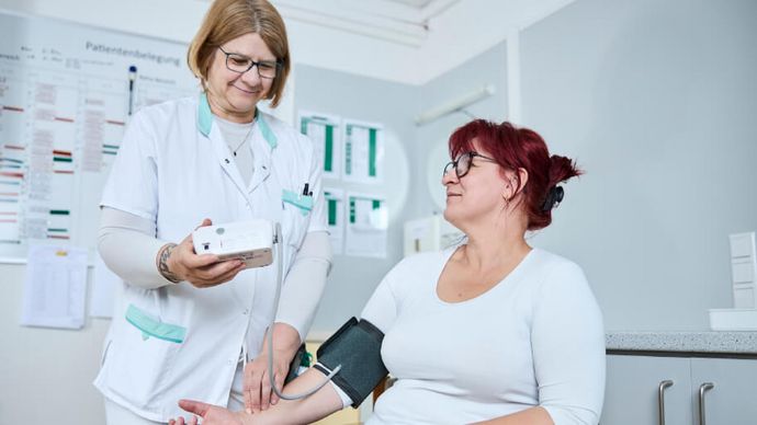 Eine Pflegekraft misst bei einer Patientin den Blutdruck